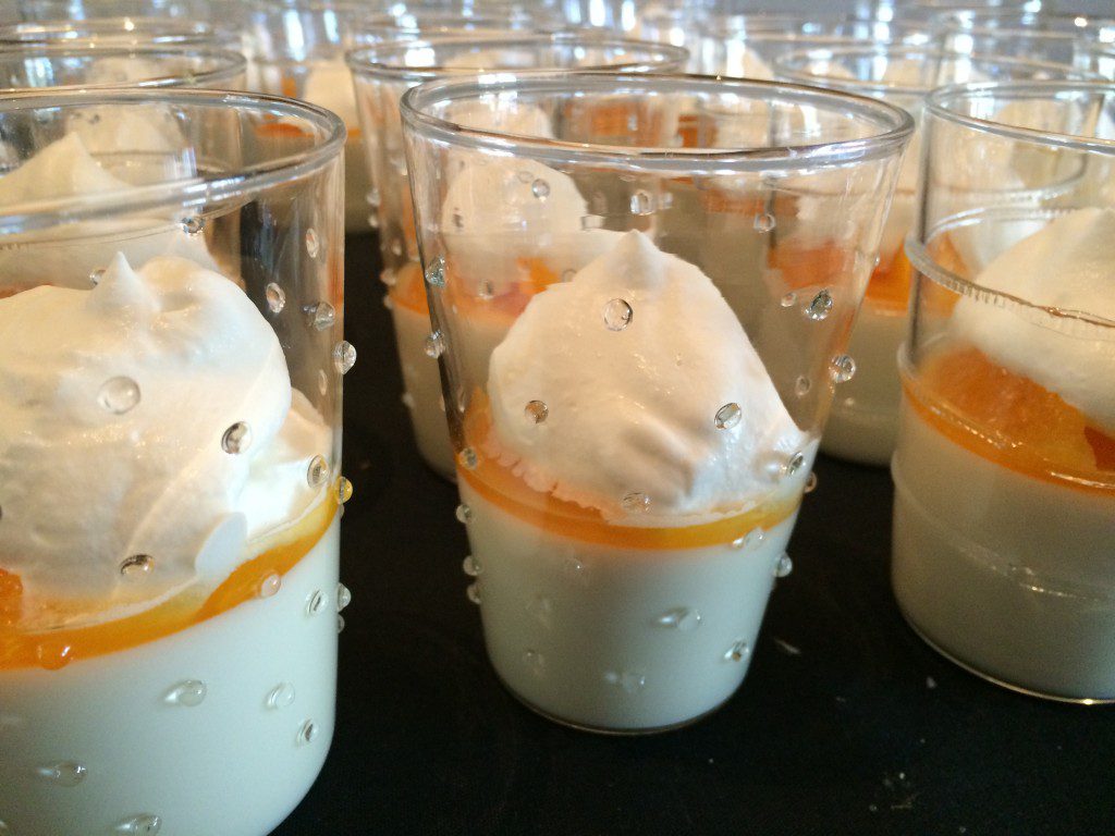 Desserts in glasses with whipped cream and oranges.