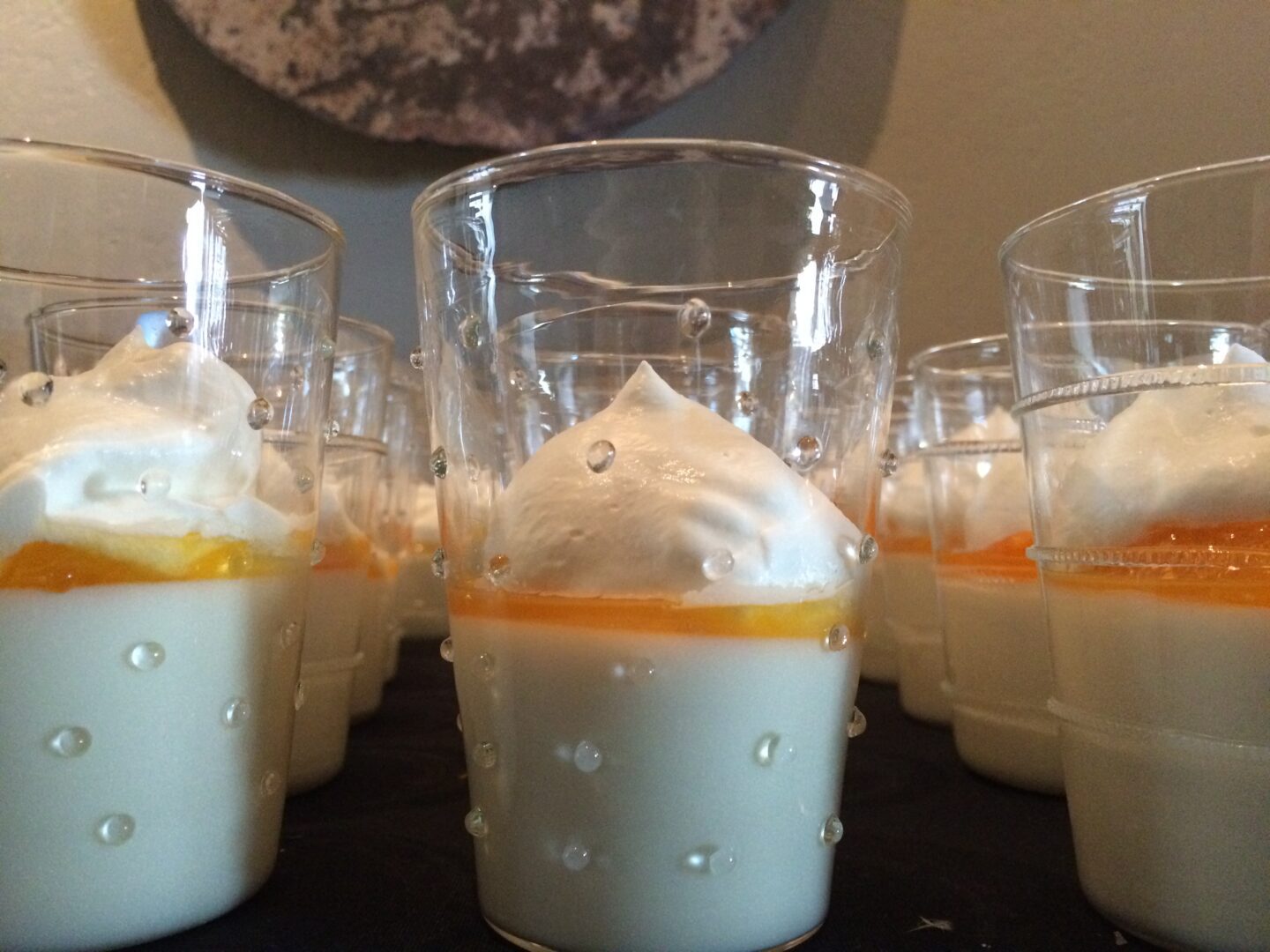 A group of glasses with whipped cream and oranges in them.