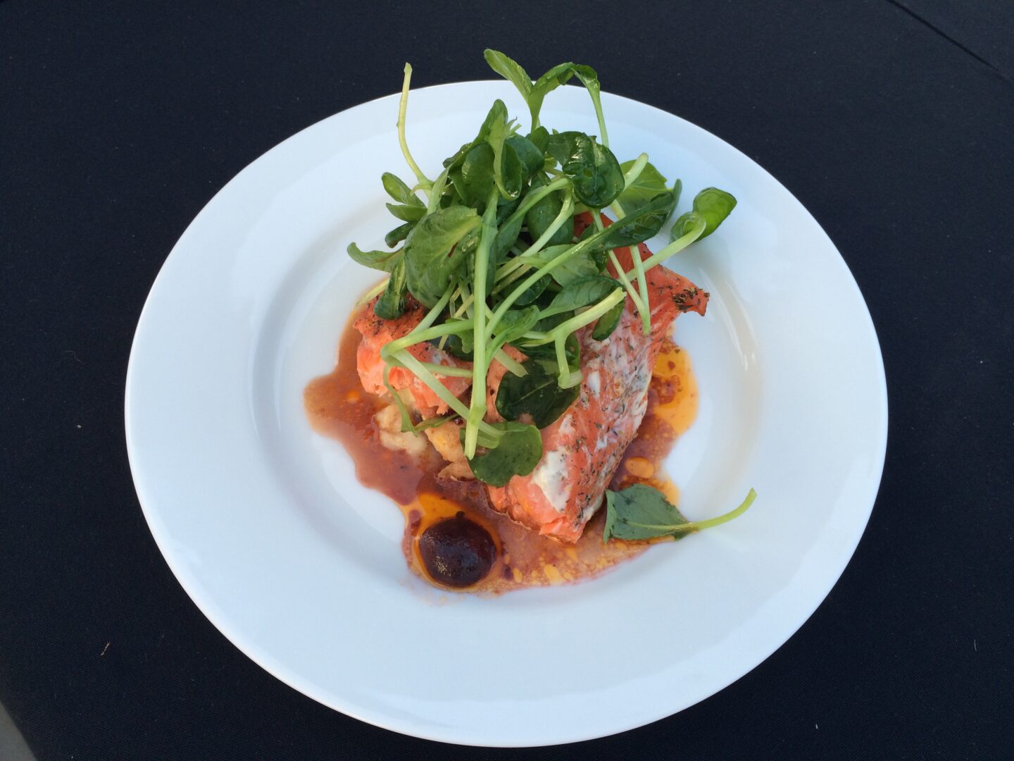 A white plate with salmon and greens on it.