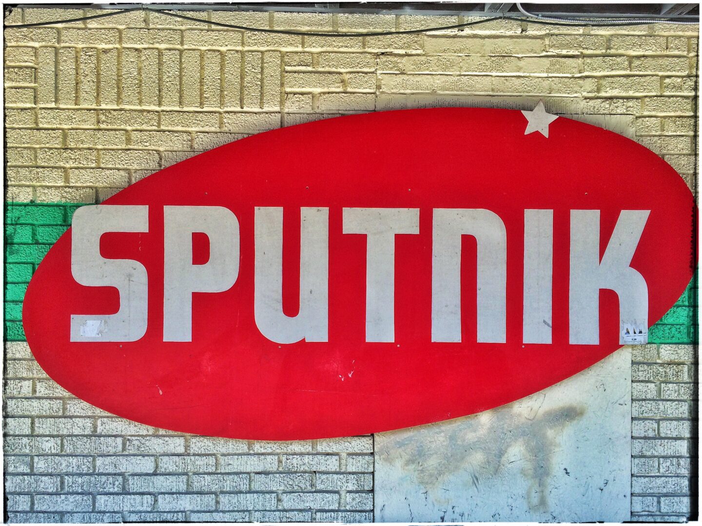 A sign that says sputnik on the side of a brick building.