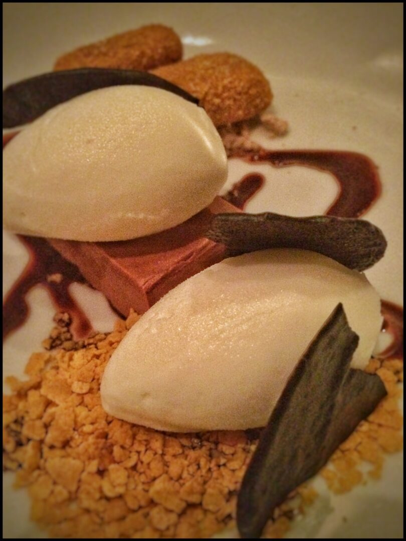A white plate with ice cream and chocolate on it.
