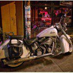 A white motorcycle parked in front of a bar.