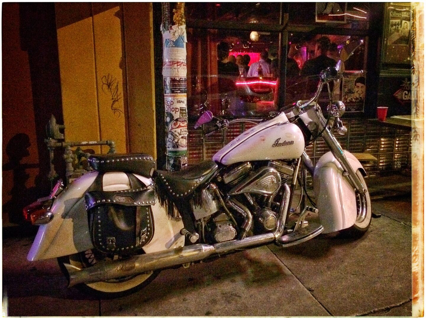 A white motorcycle parked in front of a bar.