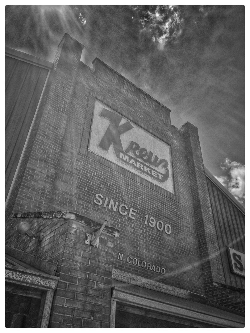 A black and white photo of a building with a sign on it.