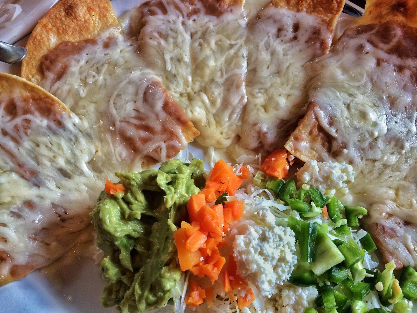 A plate of food with cheese, guacamole, and vegetables.