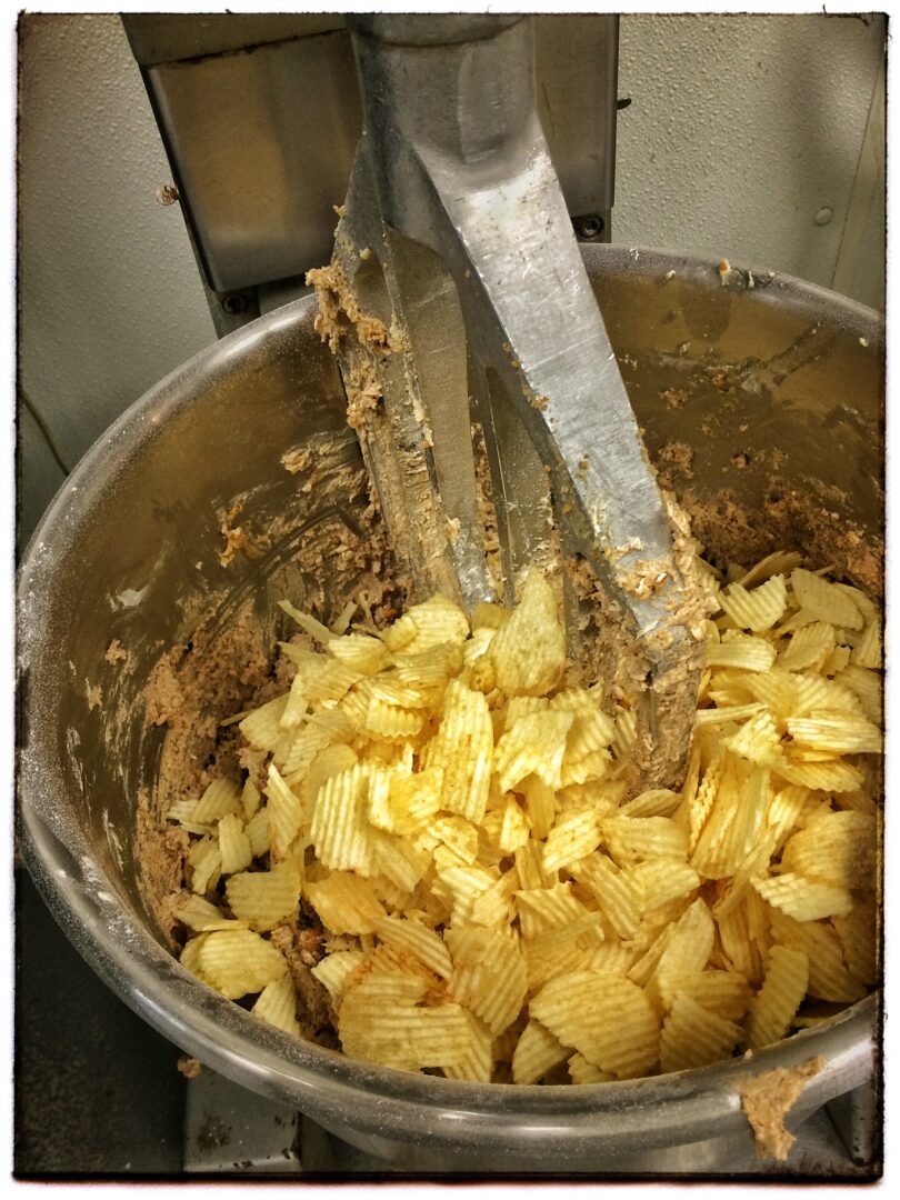 Potato chips being mixed in a mixing bowl.