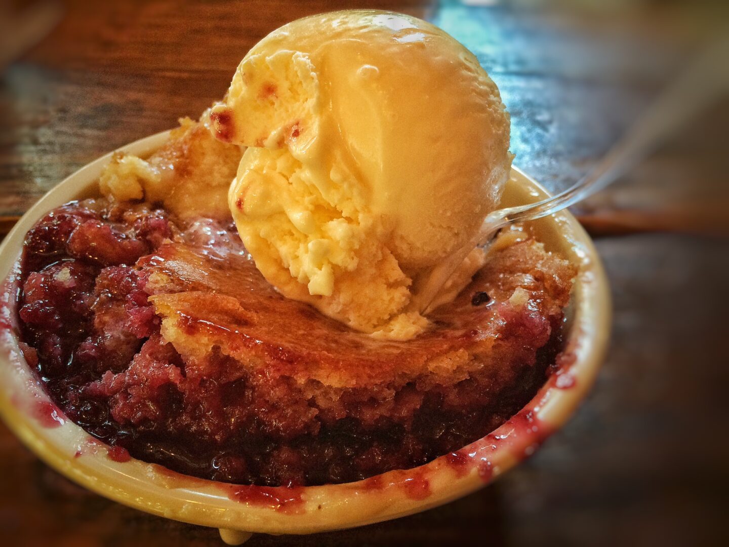 A bowl of dessert with ice cream and a scoop of ice cream.