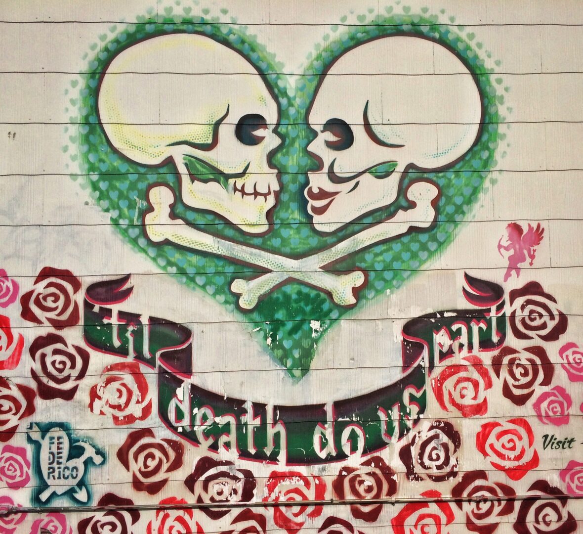 A wall with two skulls and roses painted on it.