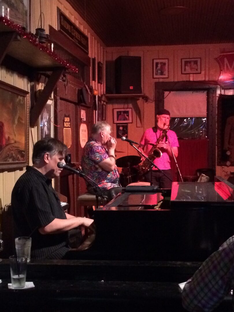 A group of people sitting at a piano in a bar.