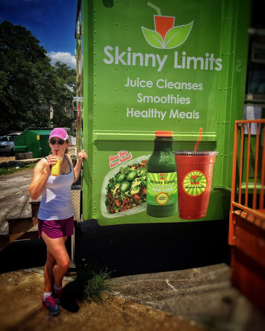 A woman standing in front of a green smoothie truck.