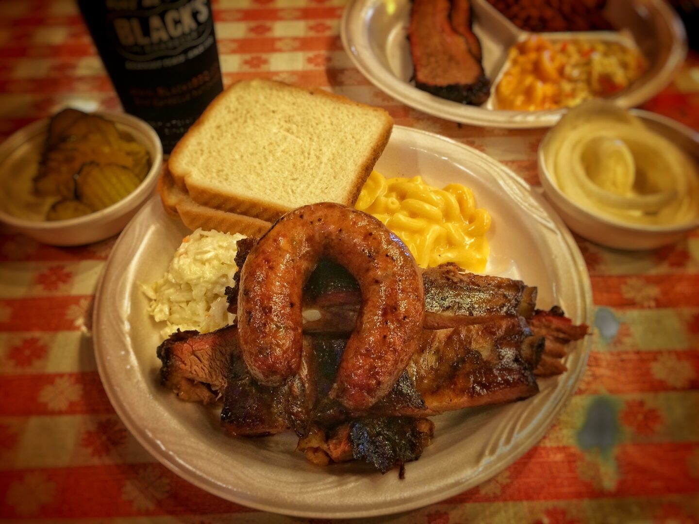 A plate of ribs, macaroni and cheese and a bottle of beer.