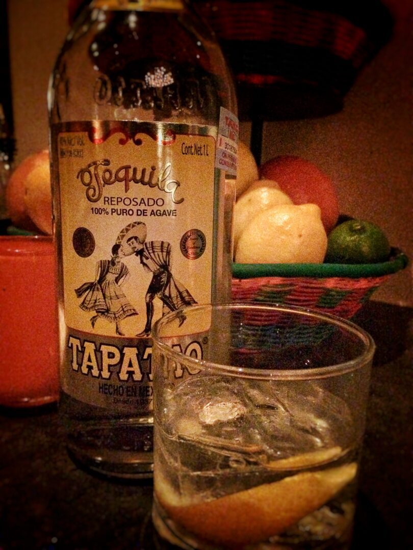 A bottle of tequila next to a glass of tequila.