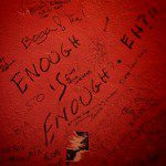 A red wall with writing on it that says enough is enough.