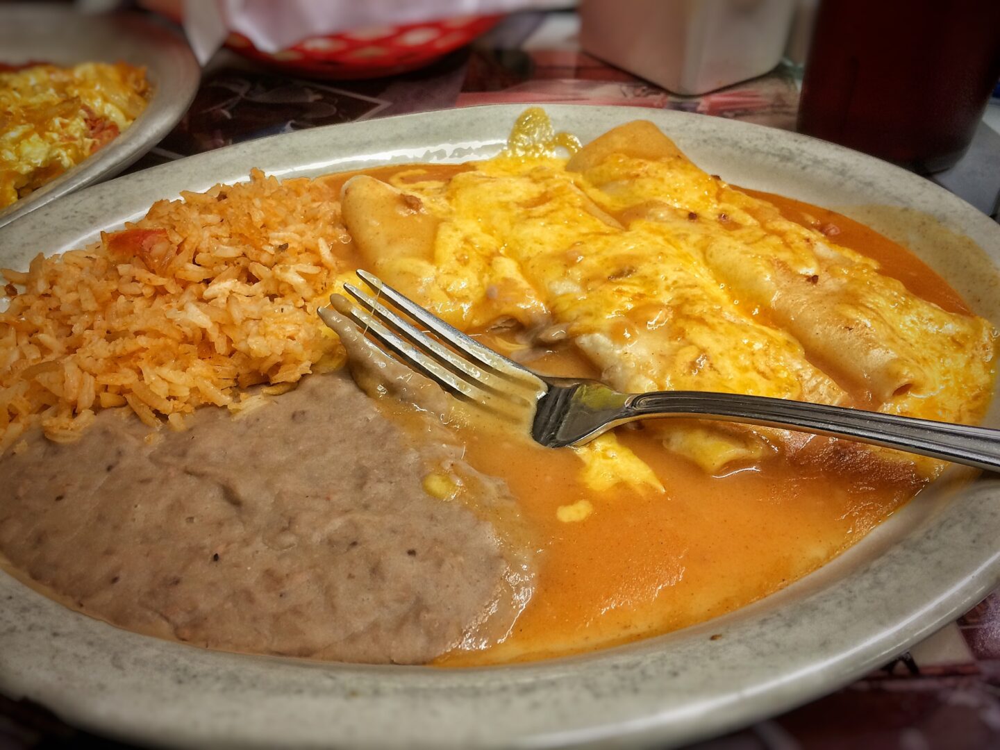 A plate of enchiladas and rice with a fork.