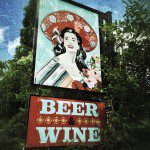 A beer and wine sign with a woman in a hat.