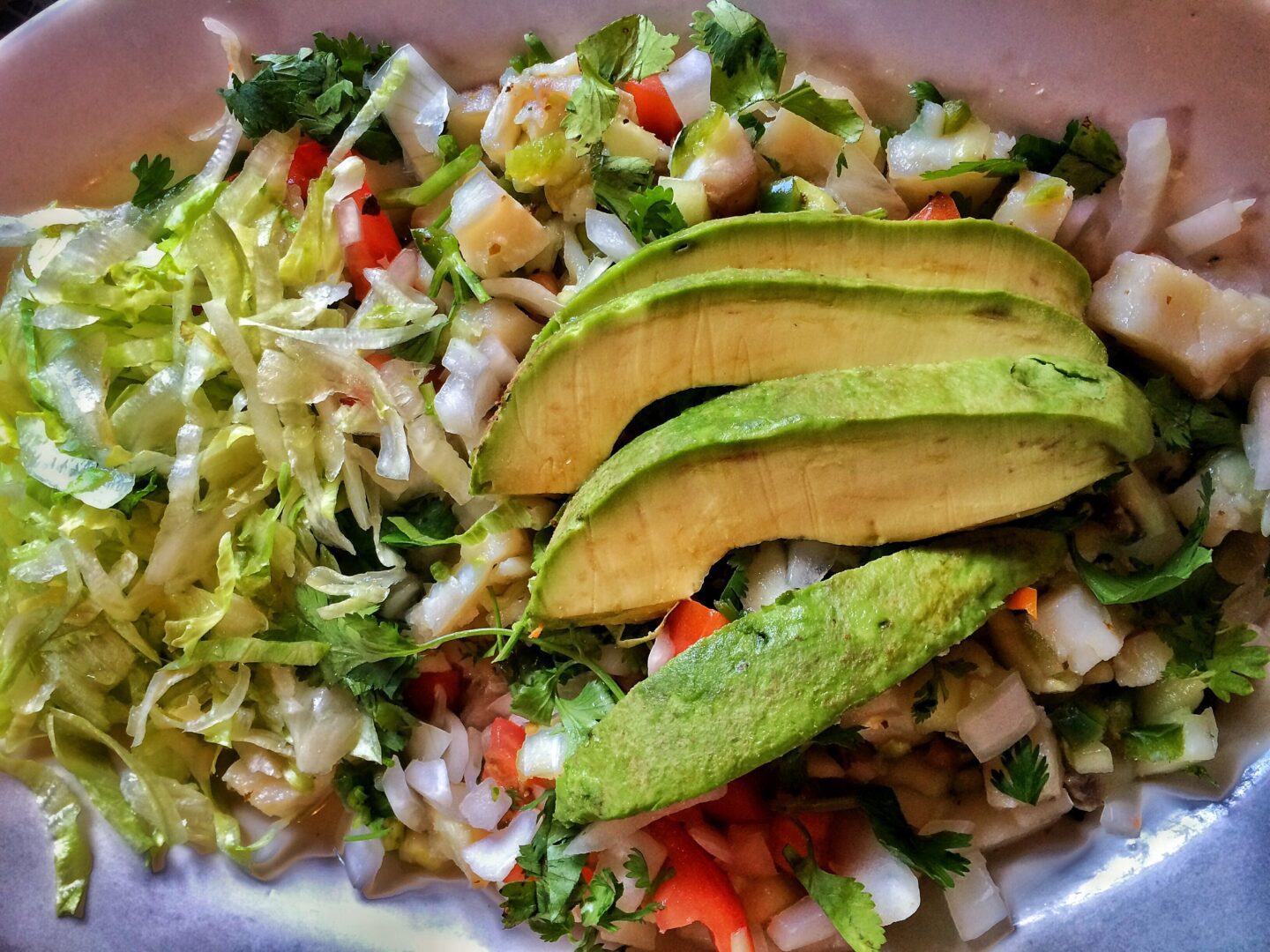 A plate with a salad and avocado on it.