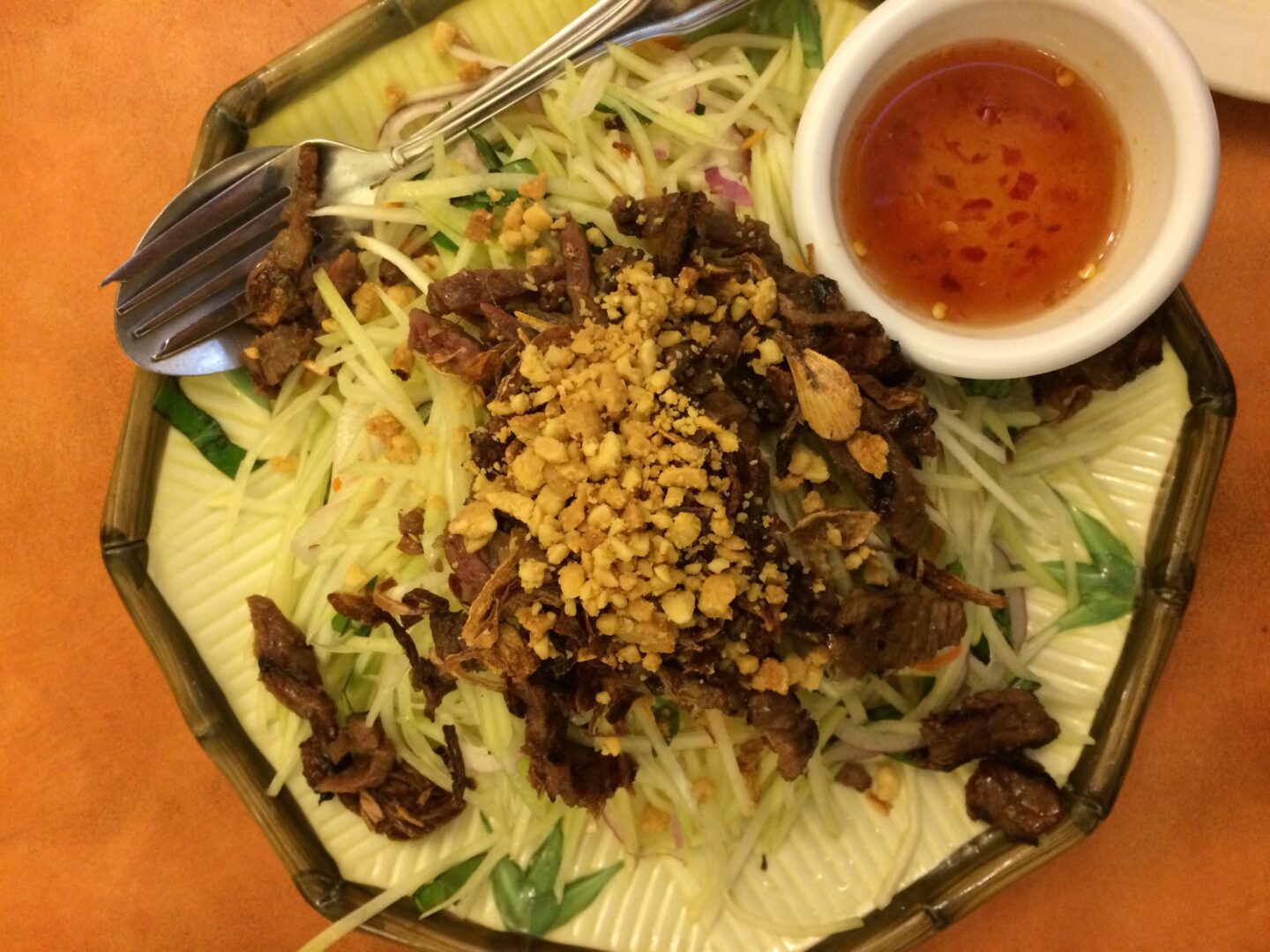 A plate of beef salad with a sauce on it.