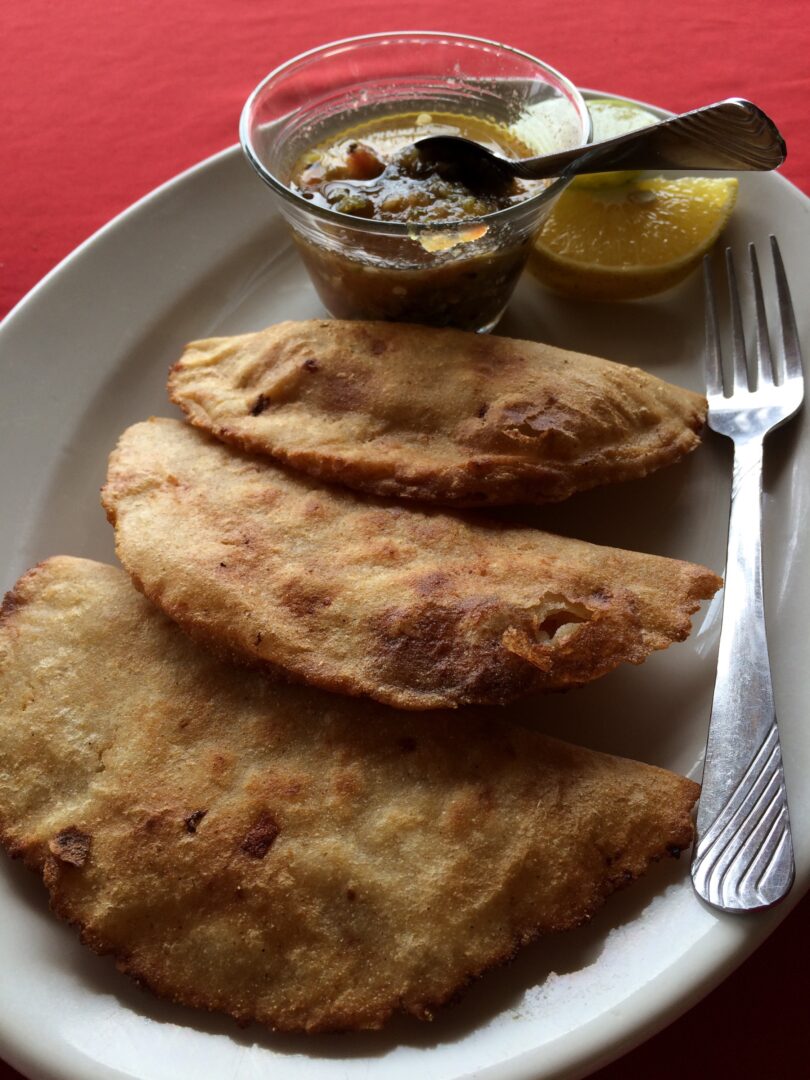 A plate of fried bread with a dipping sauce.