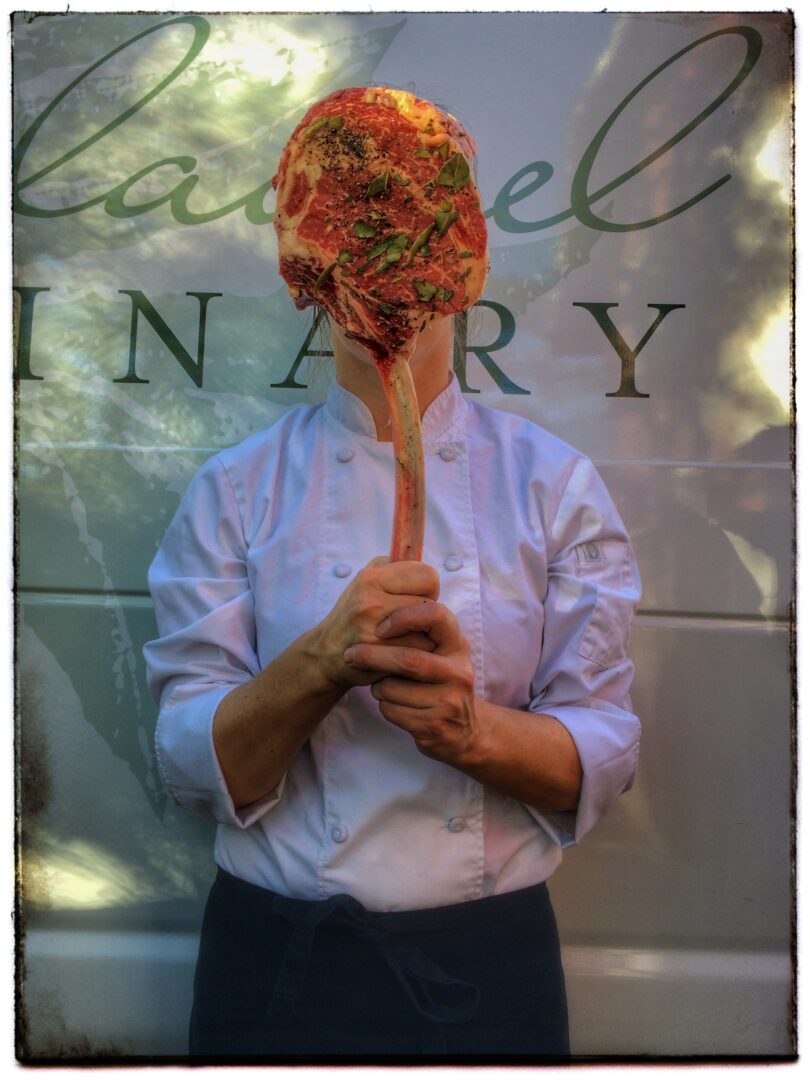 A chef holding a pizza in front of a van.