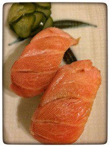 Two slices of salmon on a plate with cucumbers.