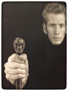 A black and white photo of a man holding a skull.
