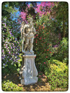 A statue in a garden surrounded by flowers.