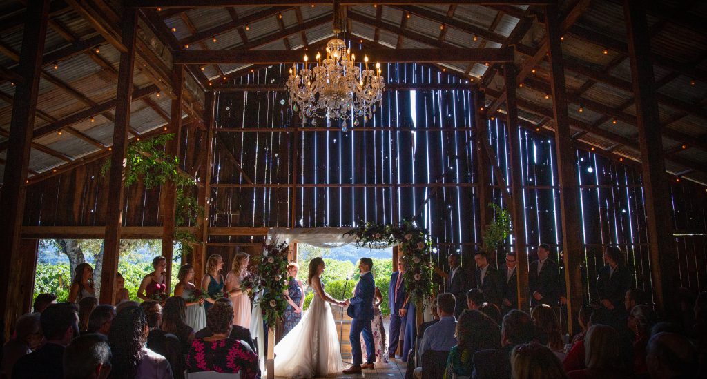 A wedding ceremony in a barn with a chandelier.