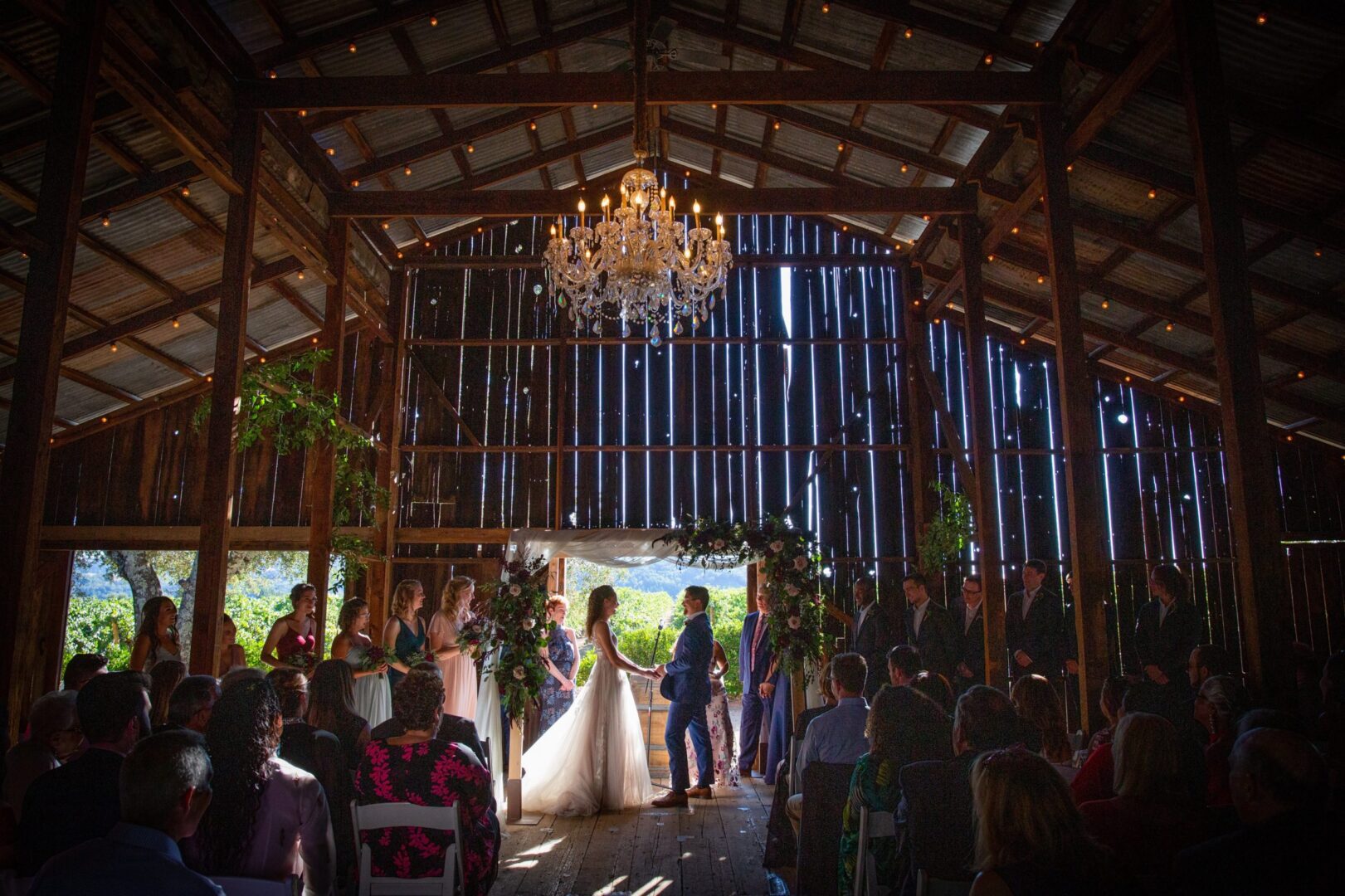 A wedding ceremony in a barn with a chandelier.