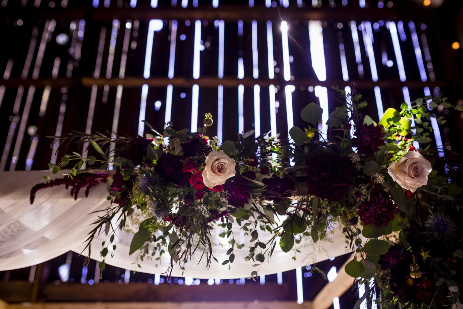 A wedding arch decorated with flowers in a barn.