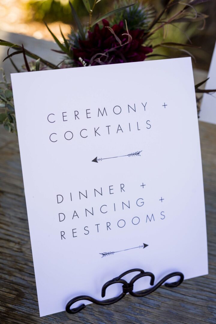 Ceremony and cocktail signs on a wooden table.