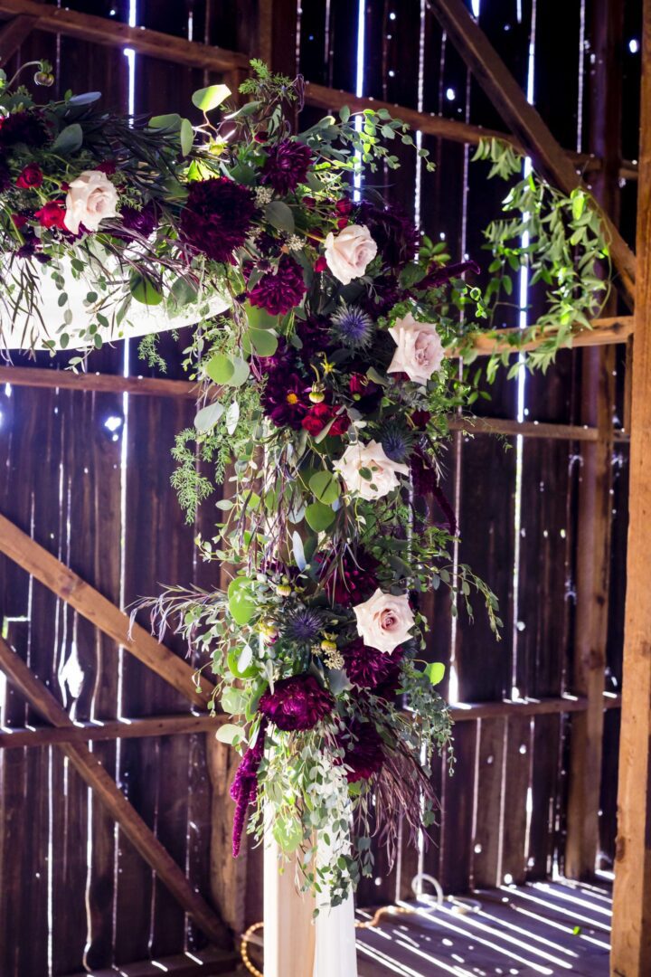 A wedding arch decorated with burgundy and purple flowers.