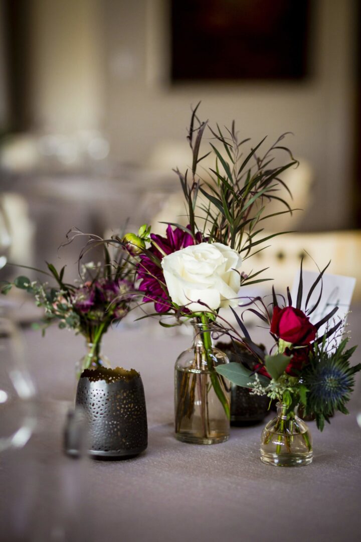 Three vases with flowers on a table.