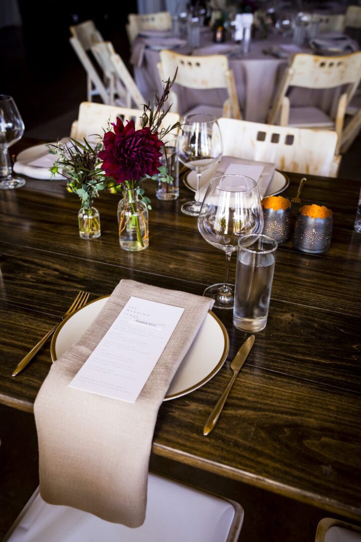 A wooden table with place settings for a wedding.