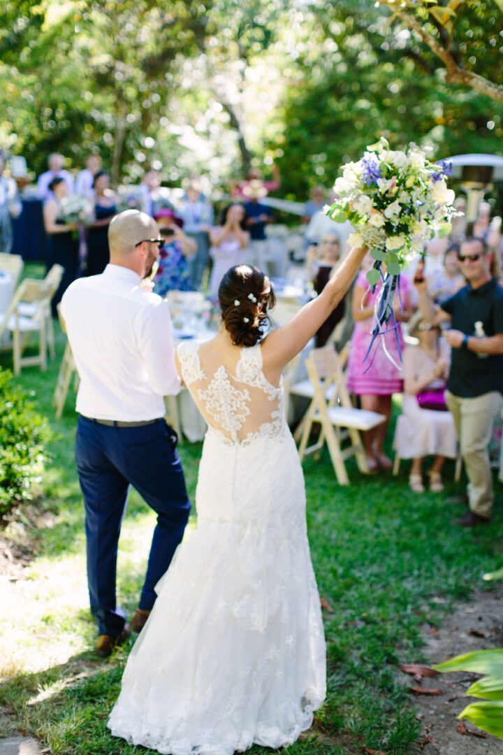 A bride and groom walking down the aisle in a garden.