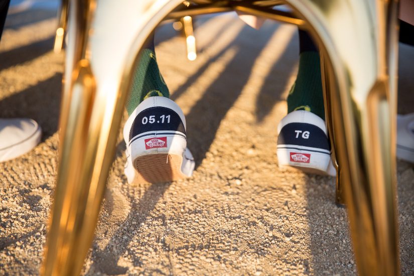 A pair of gold shoes on a table in the sand.