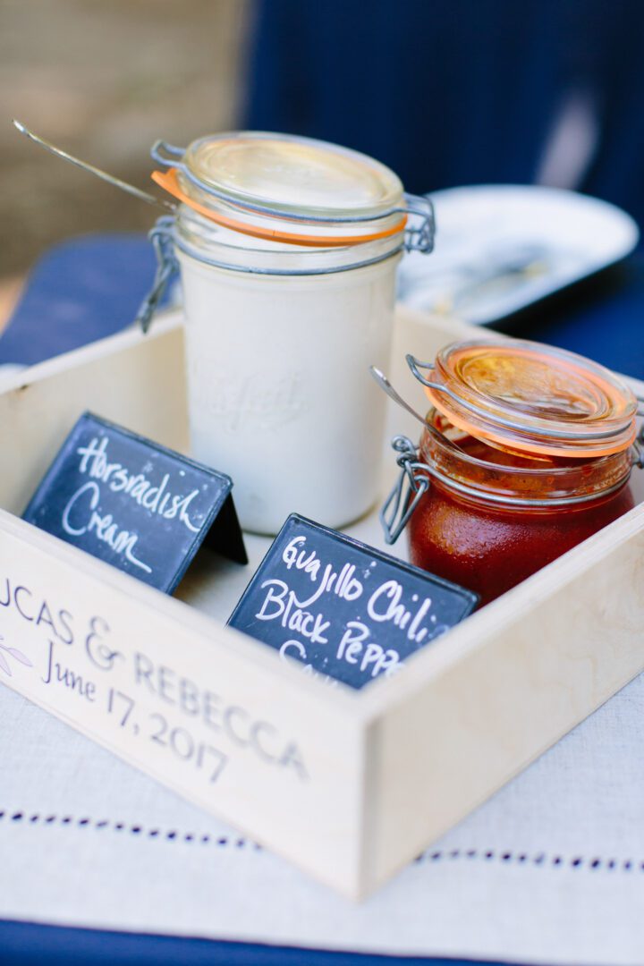 Two jars of sauce on a wooden tray.