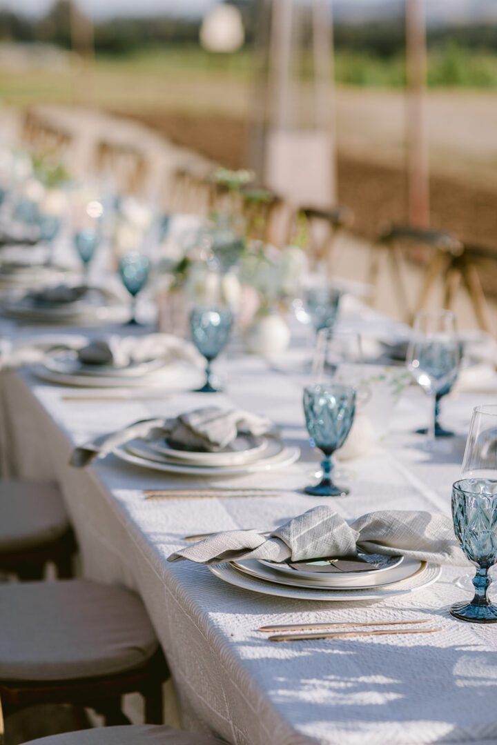 A long table set with blue plates and silverware.