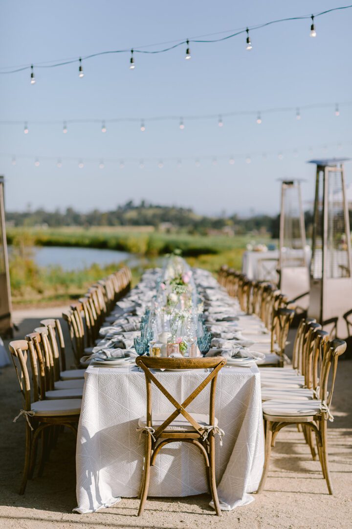 A long table set up in a field with string lights.
