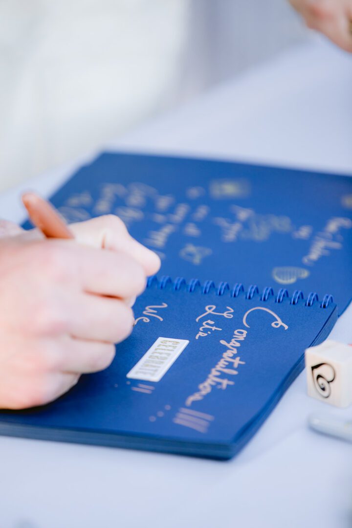 A person writing on a blue notebook.