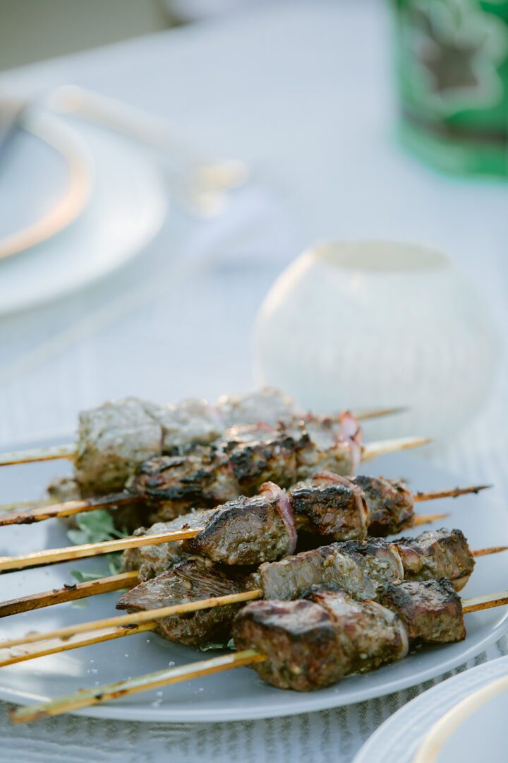 A plate of meat skewers on a table.