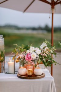 A table set up with flowers and candles under an umbrella.