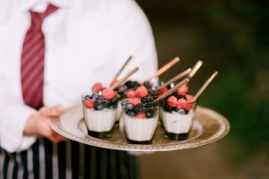 A waiter is holding a tray of desserts.