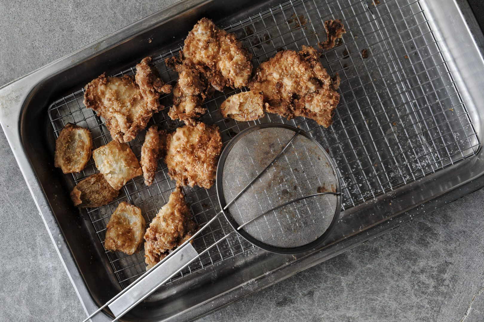 Fried chicken on a tray with a spatula.
