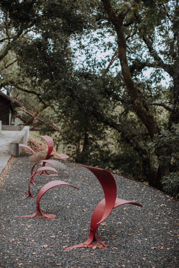 A group of red sculptures on a gravel path.
