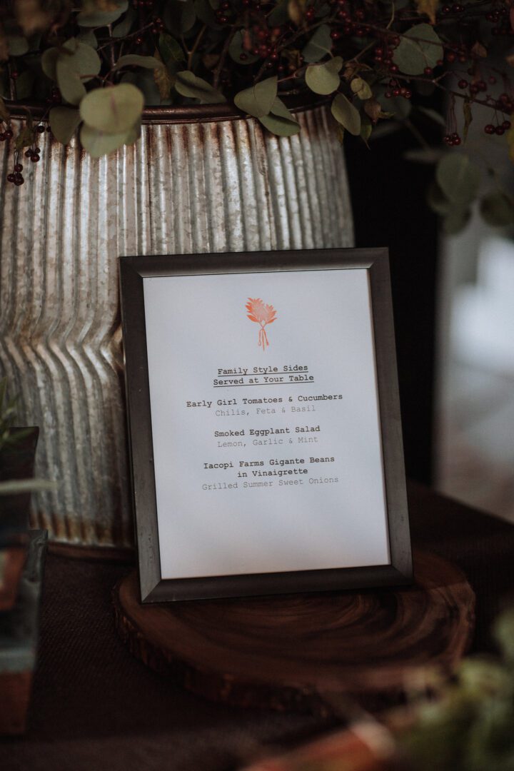 A framed menu sitting on a table next to a potted plant.