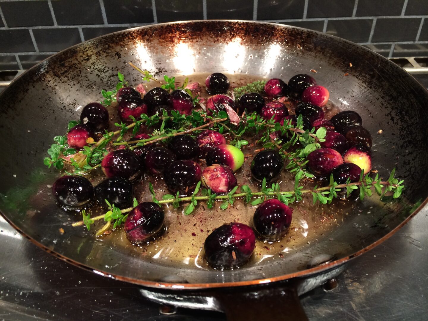 A frying pan filled with blackberries and thyme.