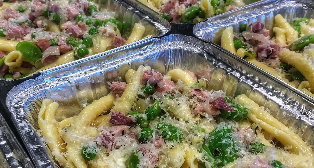 A tray of pasta with ham and peas.