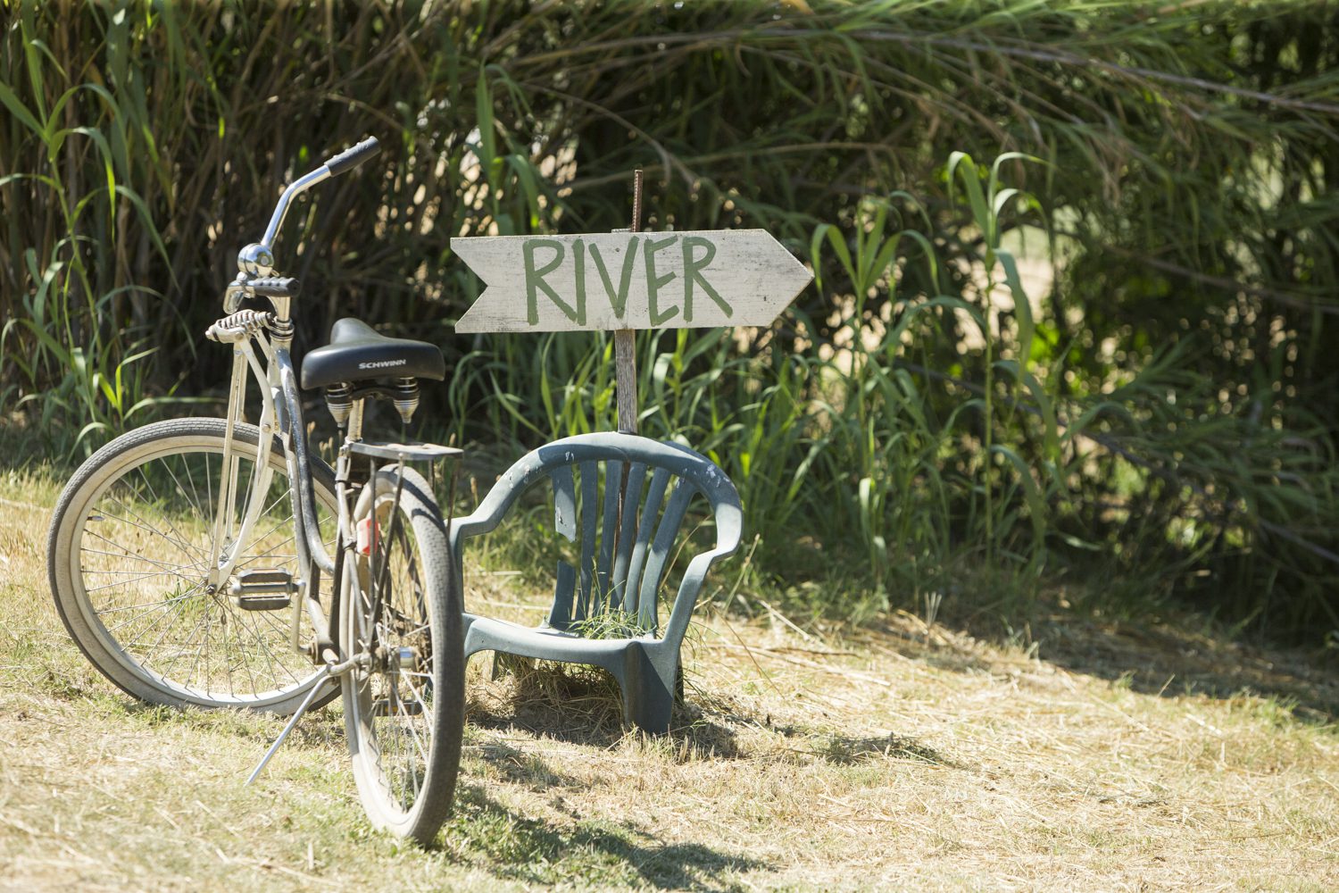 A bicycle is parked next to a chair and a sign.