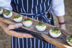 Deviled eggs on a wooden tray.