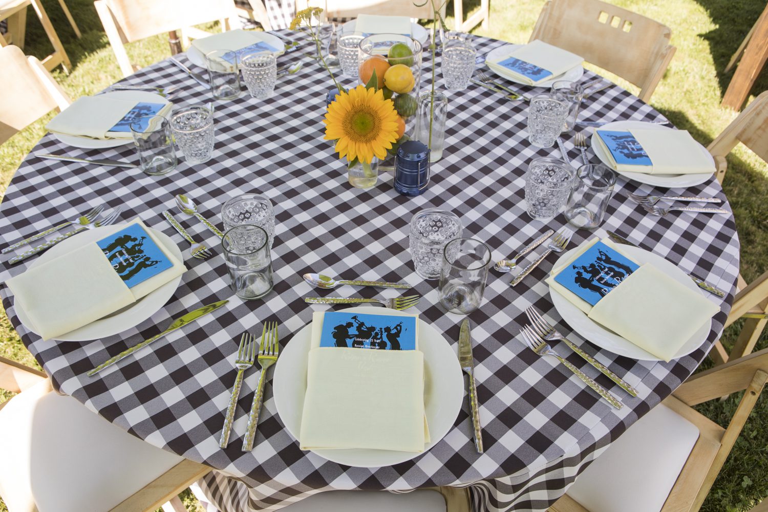 A table setting with a checkered tablecloth and sunflowers.